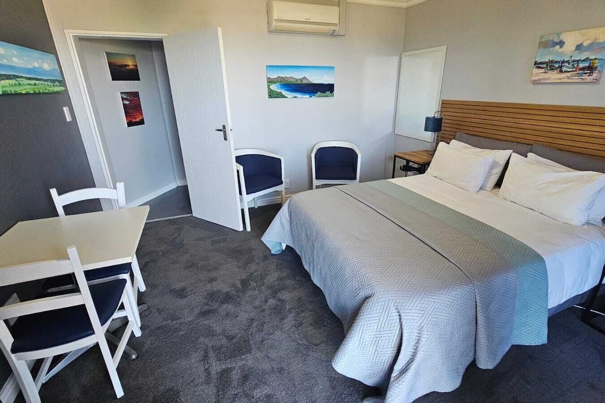 A hotel room with a bed, a desk, two chairs, and a small table.