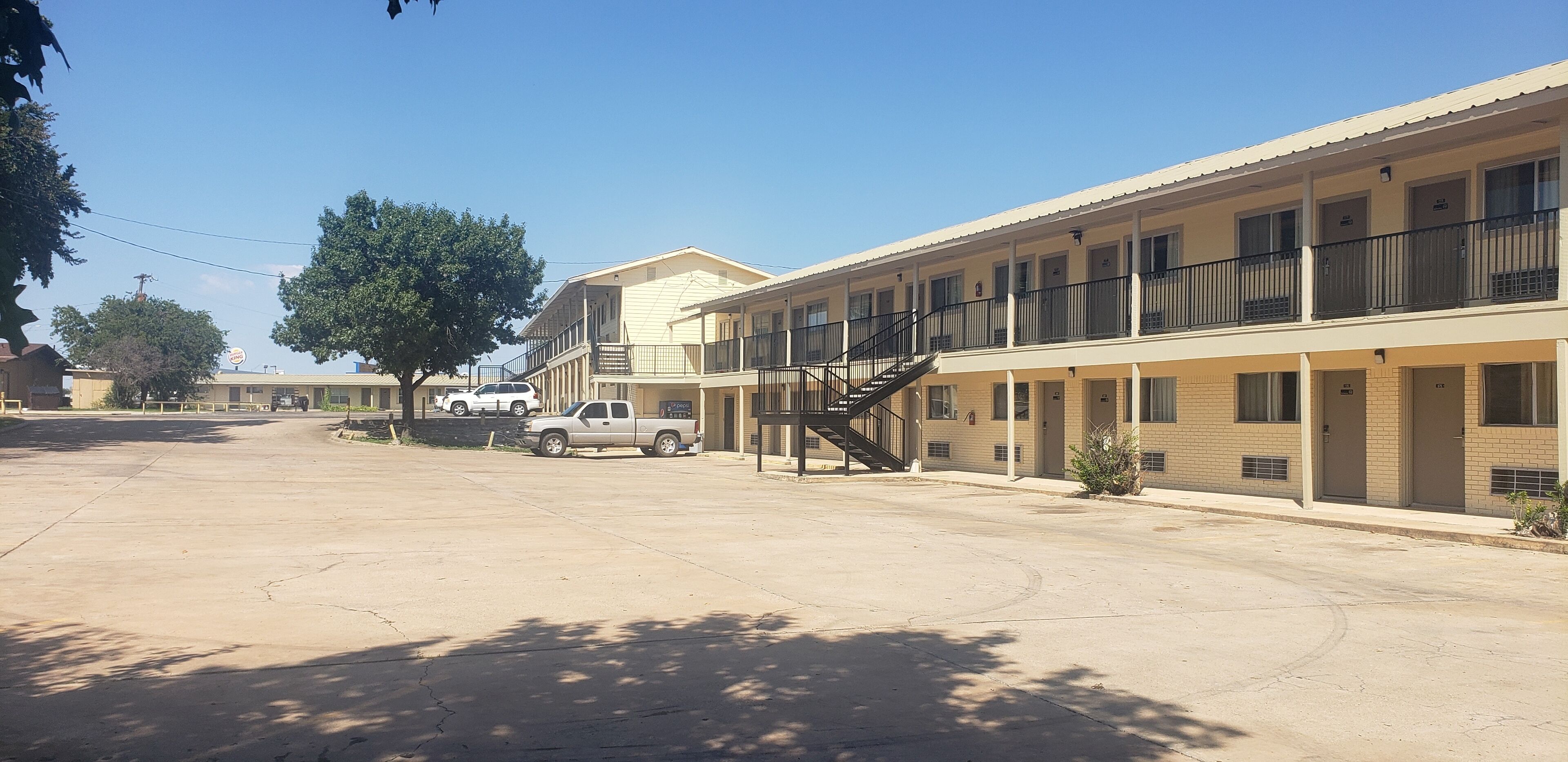 A motel with a central staircase, multiple balconies, and a parking area.