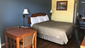 A hotel room with a bed, a desk, a chair, two bedside lamps, and a painting on the wall. - Gold Key Inn (Brady)