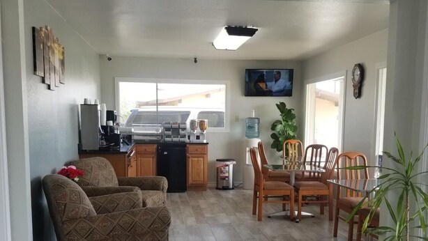 A spacious living area with a dining table and chairs, a kitchen with a refrigerator and coffee maker, and a large window providing natural light. - Gold Key Inn (Brady)