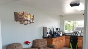 A modern kitchen with wooden cabinets, a coffee machine, and a dining area with two patterned armchairs. - Gold Key Inn (Brady)