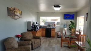 A compact living space with a kitchenette, a dining area, and a seating area with patterned sofas. - Gold Key Inn (Brady)