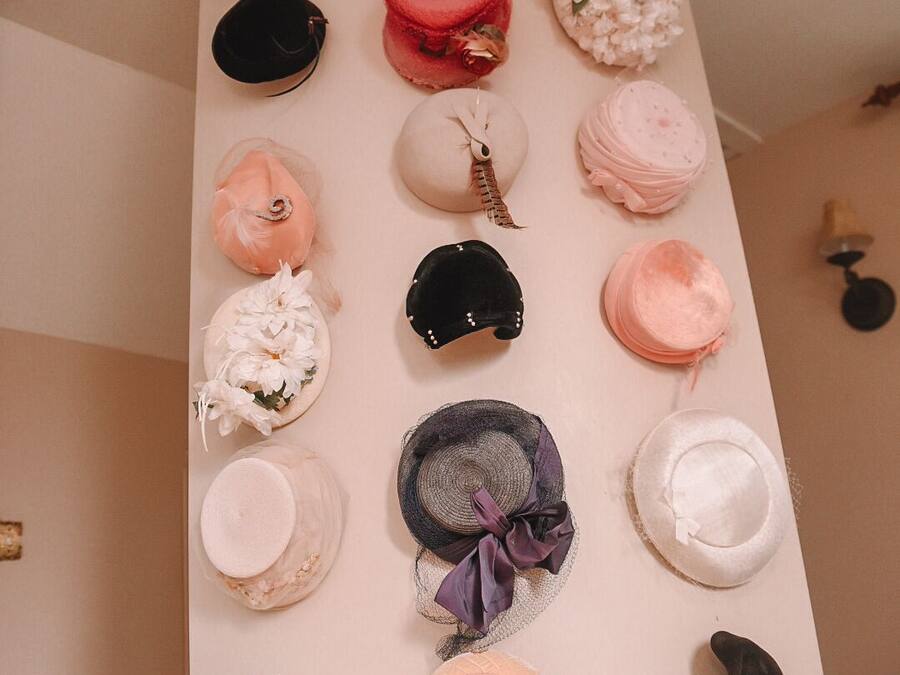 Una pared con varios sombreros exhibidos en fila.