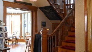 Un magnifique escalier, avec des marches recouvertes de moquette rouge, menant à un deuxième étage, des rampes en bois et un lustre.