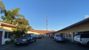 A street with parked cars and buildings, including a motel with a red roof. - Sands Inn (South Gate)
