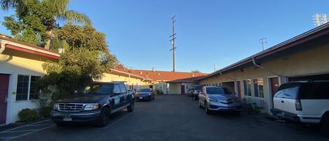 A street with parked cars and buildings, including a motel with a red roof.