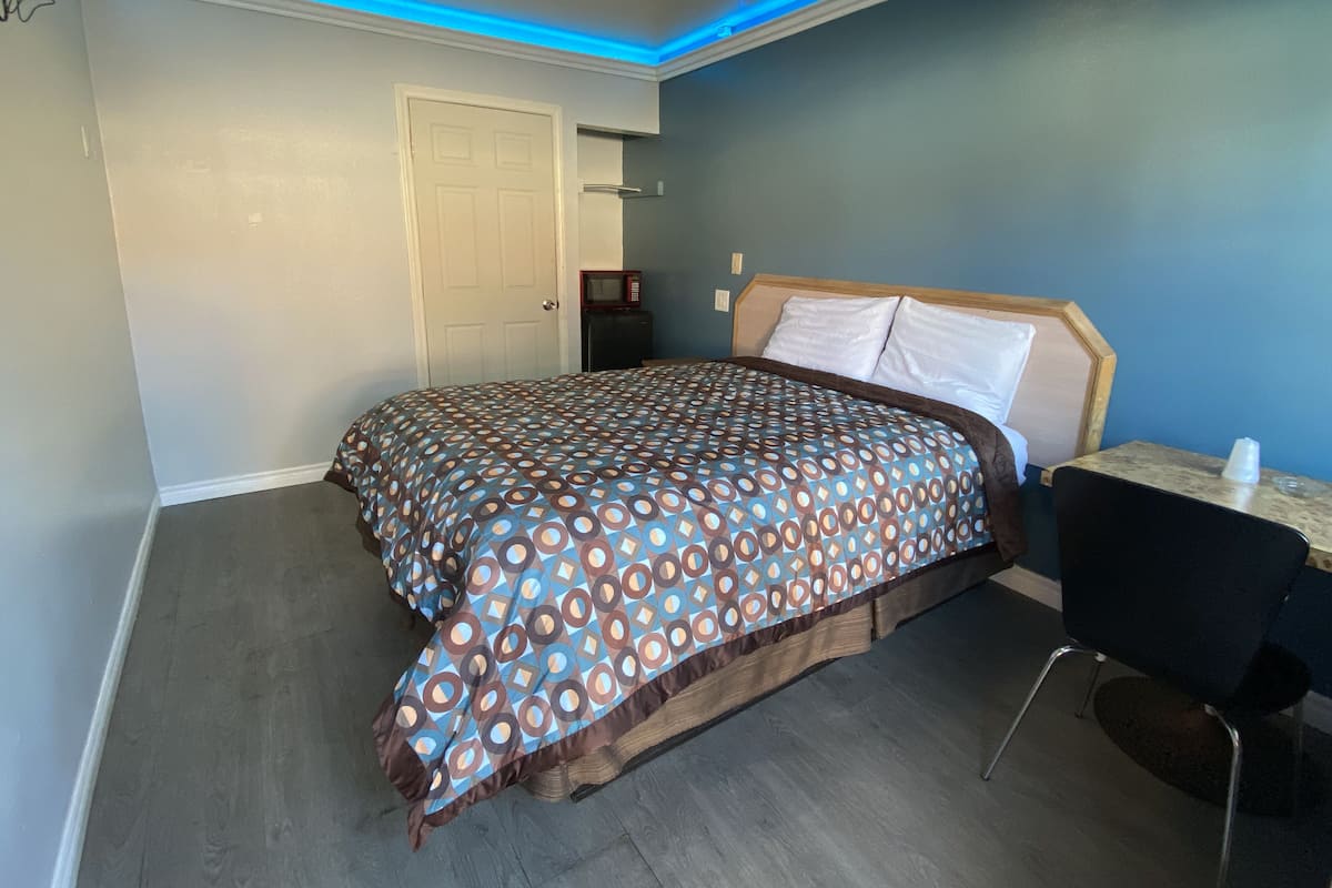 Un dormitorio con una colcha estampada, un cabecero de madera, una mesita de noche y una silla.
