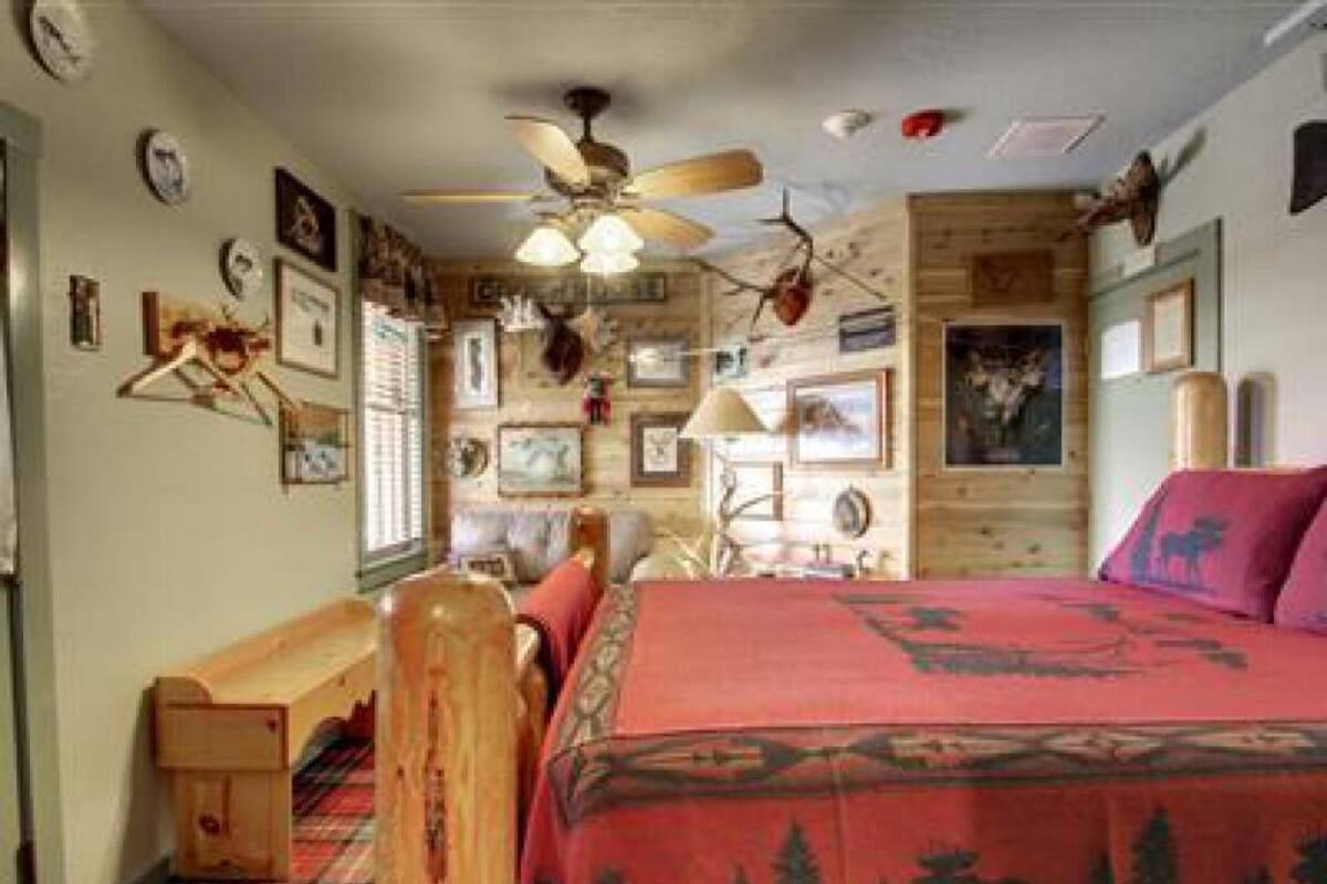 A room with a bed, a wooden bench, and a ceiling fan.