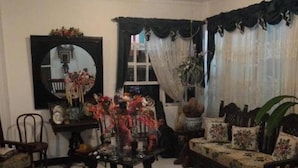 Ein gemütliches Wohnzimmer mit einer Couch, Sesseln, einem Couchtisch und einem Spiegel.