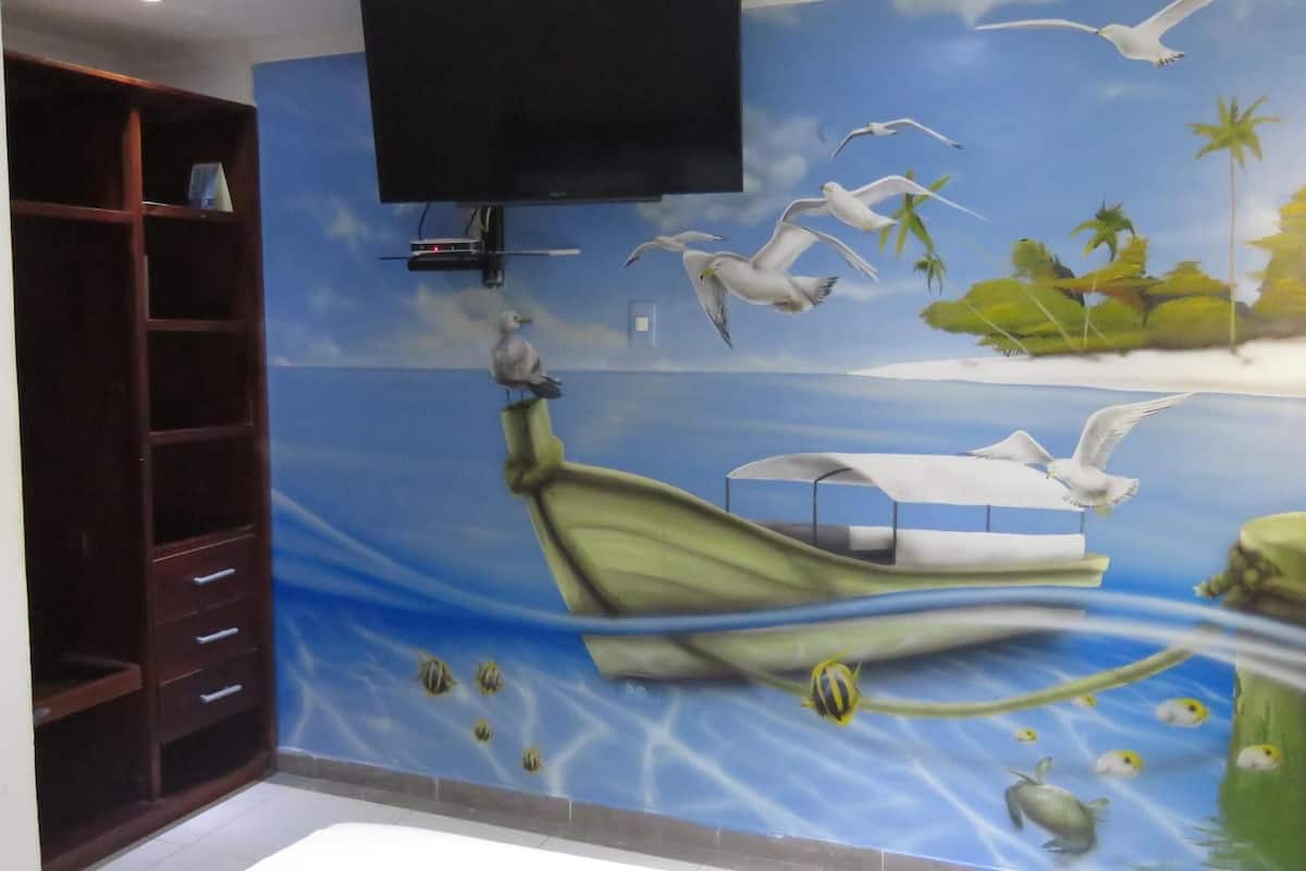 A room with a mural of a boat on water, seagulls, and tropical scenery.