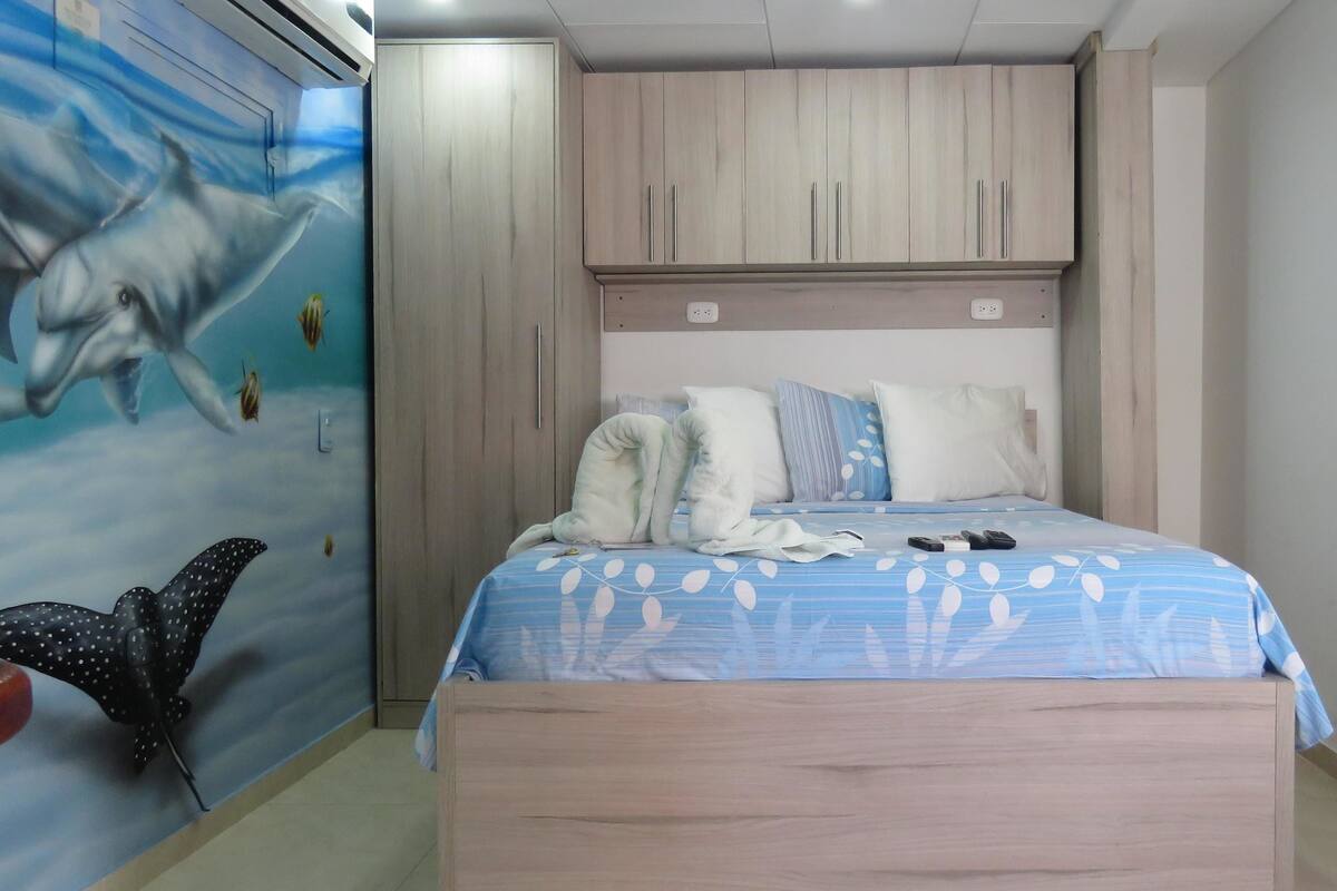 A bedroom with a bed, a wardrobe, and a wall mural.