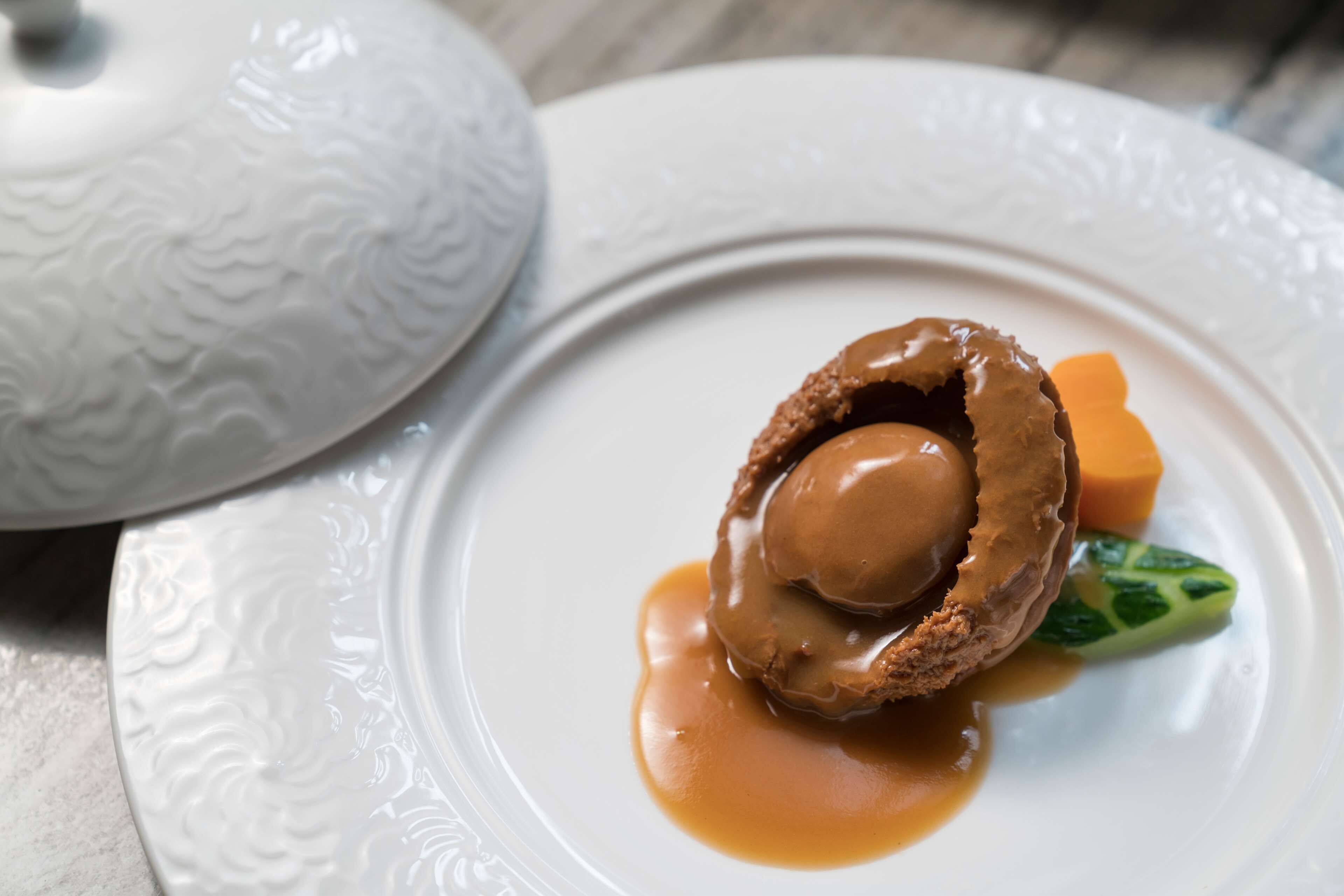 A dessert on a white plate with a caramel sauce and a green leaf garnish.