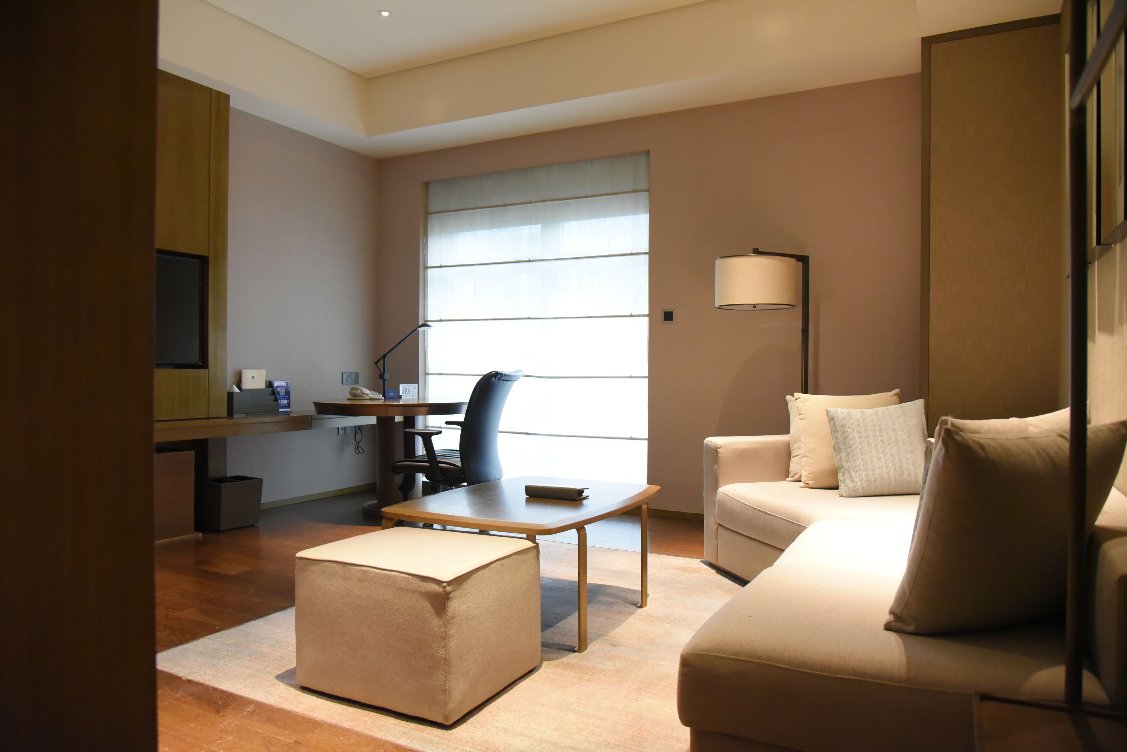Habitació d'hotel moderna amb sofà, otomà, escriptori i cadira.