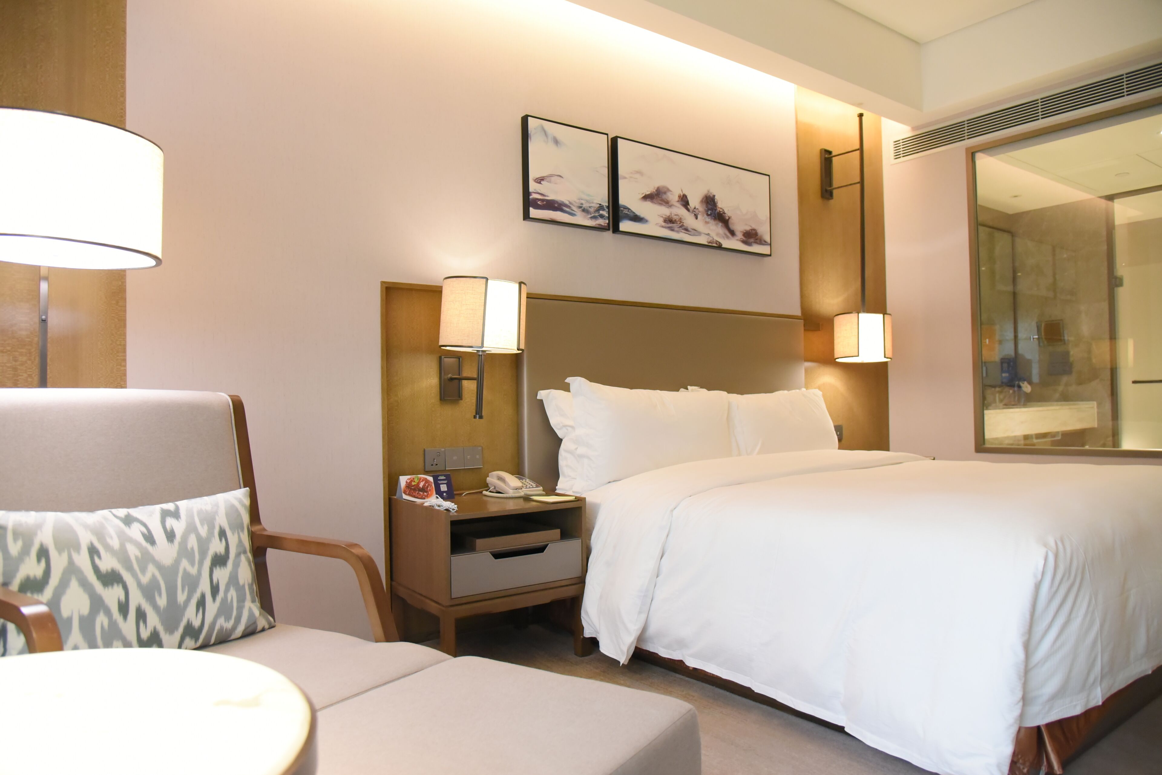 Una habitación de hotel con cama, una silla, una mesita de noche y una lámpara.