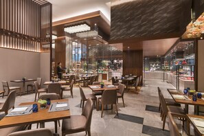 A modern restaurant with wooden tables and chairs, a bar area, and a view of the kitchen. - DoubleTree by Hilton Hotel Shiyan (Shiyan)