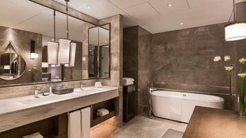 Un baño moderno con un espejo grande, dos lavamanos, una bañera y una ducha.