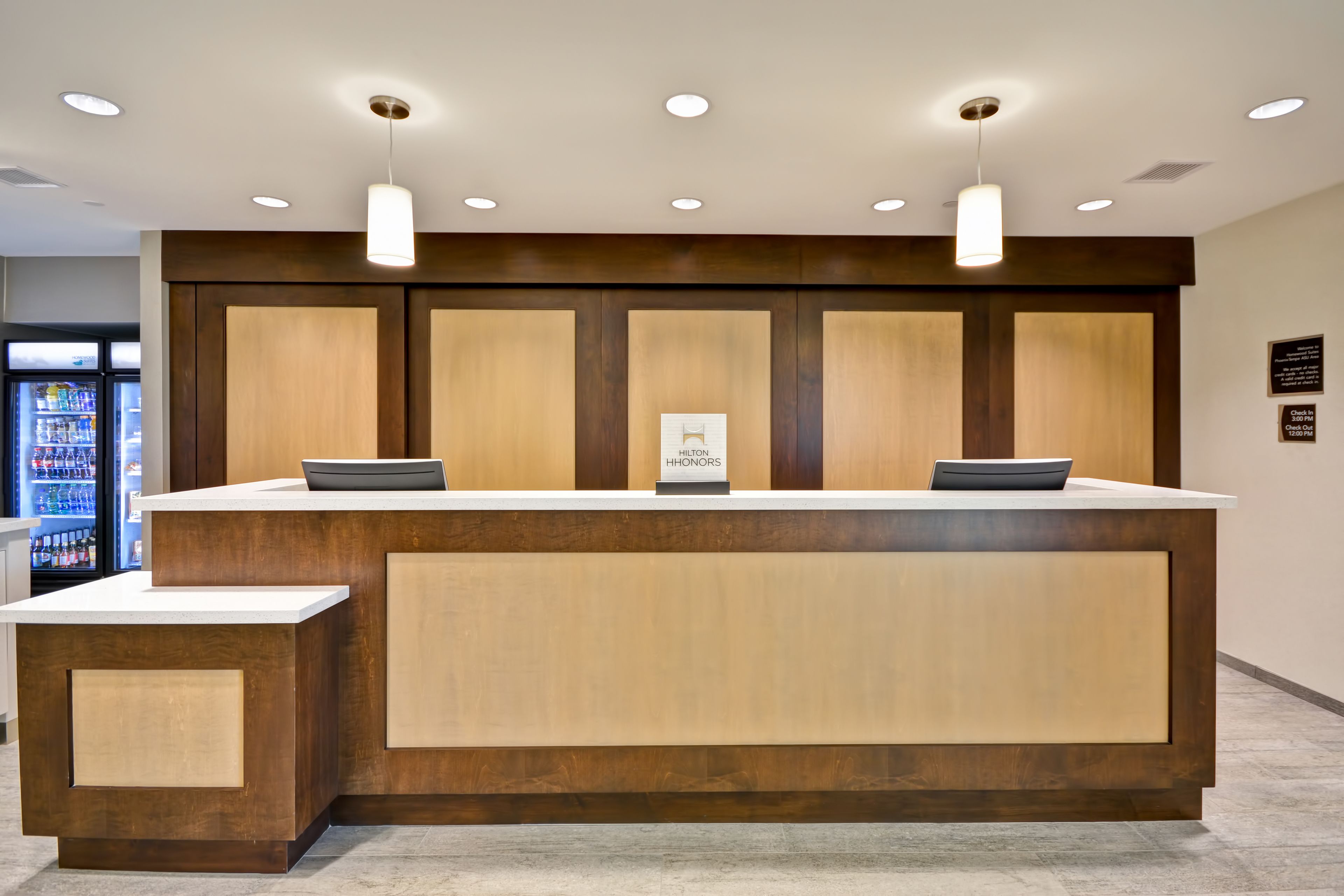 Un comptoir d’accueil avec un revêtement en bois, un plan de travail blanc et une enseigne indiquant qu’il fait partie de l’hôtel Hilton Honors.