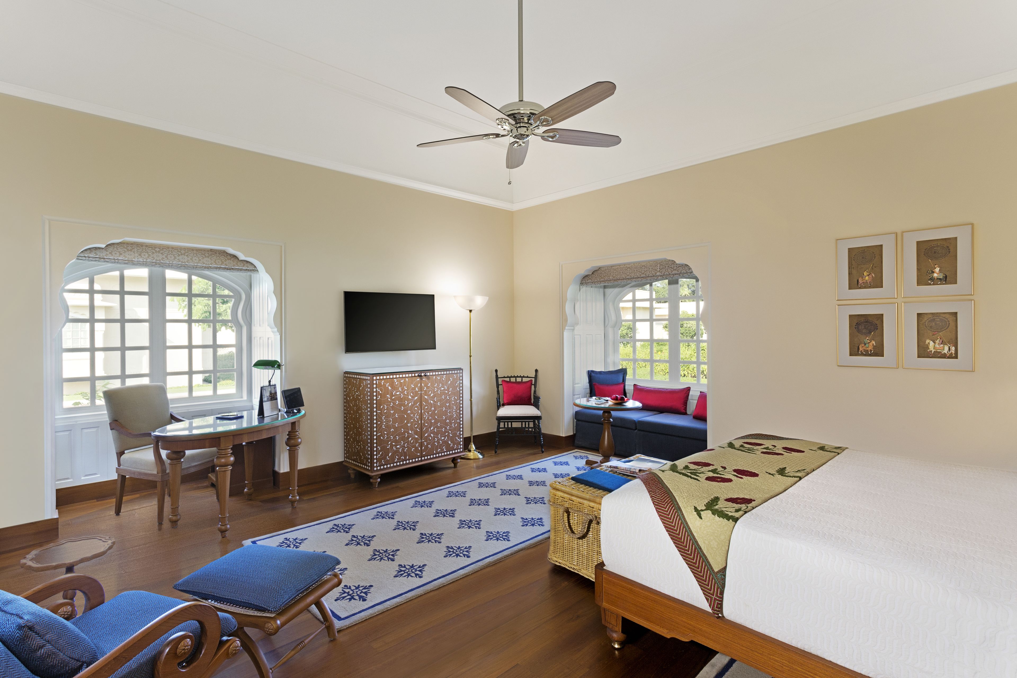 A hotel room with a bed, a desk, a chair, a television, and a window.