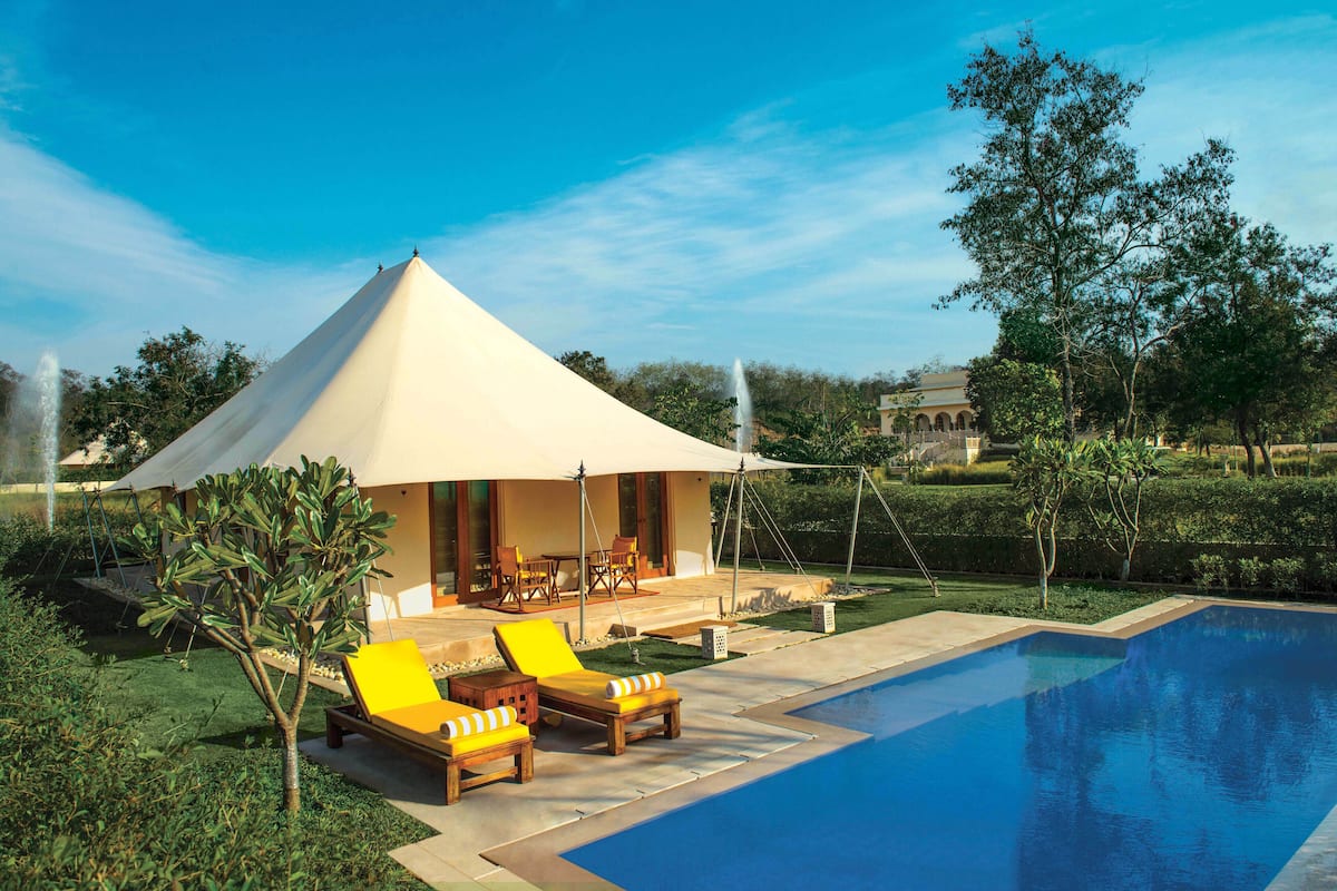 A poolside area with lounge chairs, a tent, and a clear blue sky.