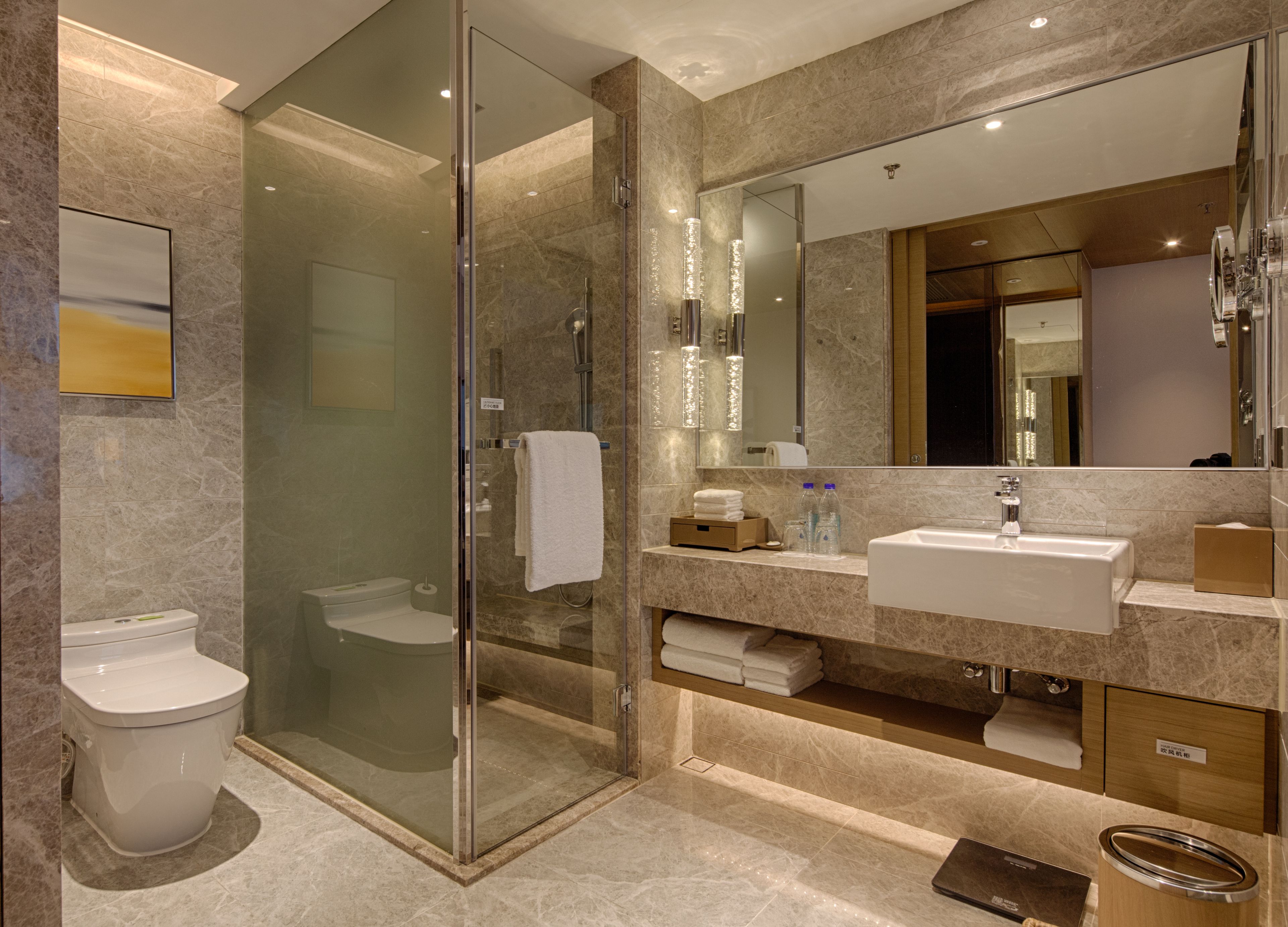 A modern bathroom with a glass-enclosed shower, a white toilet, and a vanity with a sink and mirror.