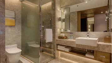 A modern bathroom with a glass-enclosed shower, a white toilet, and a vanity with a sink and mirror.