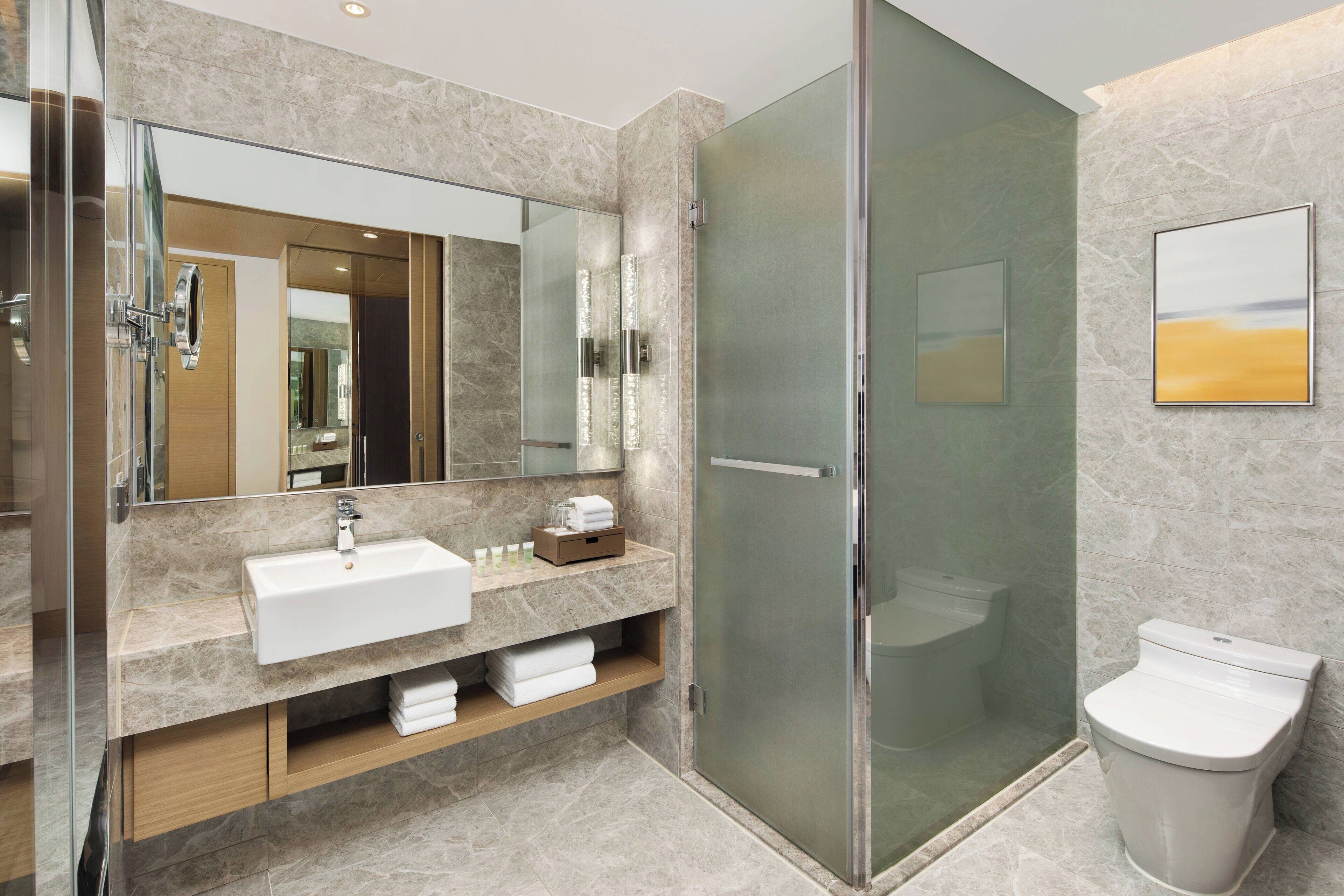 A modern bathroom with a glass-enclosed shower, a sink with a marble countertop, and a toilet.