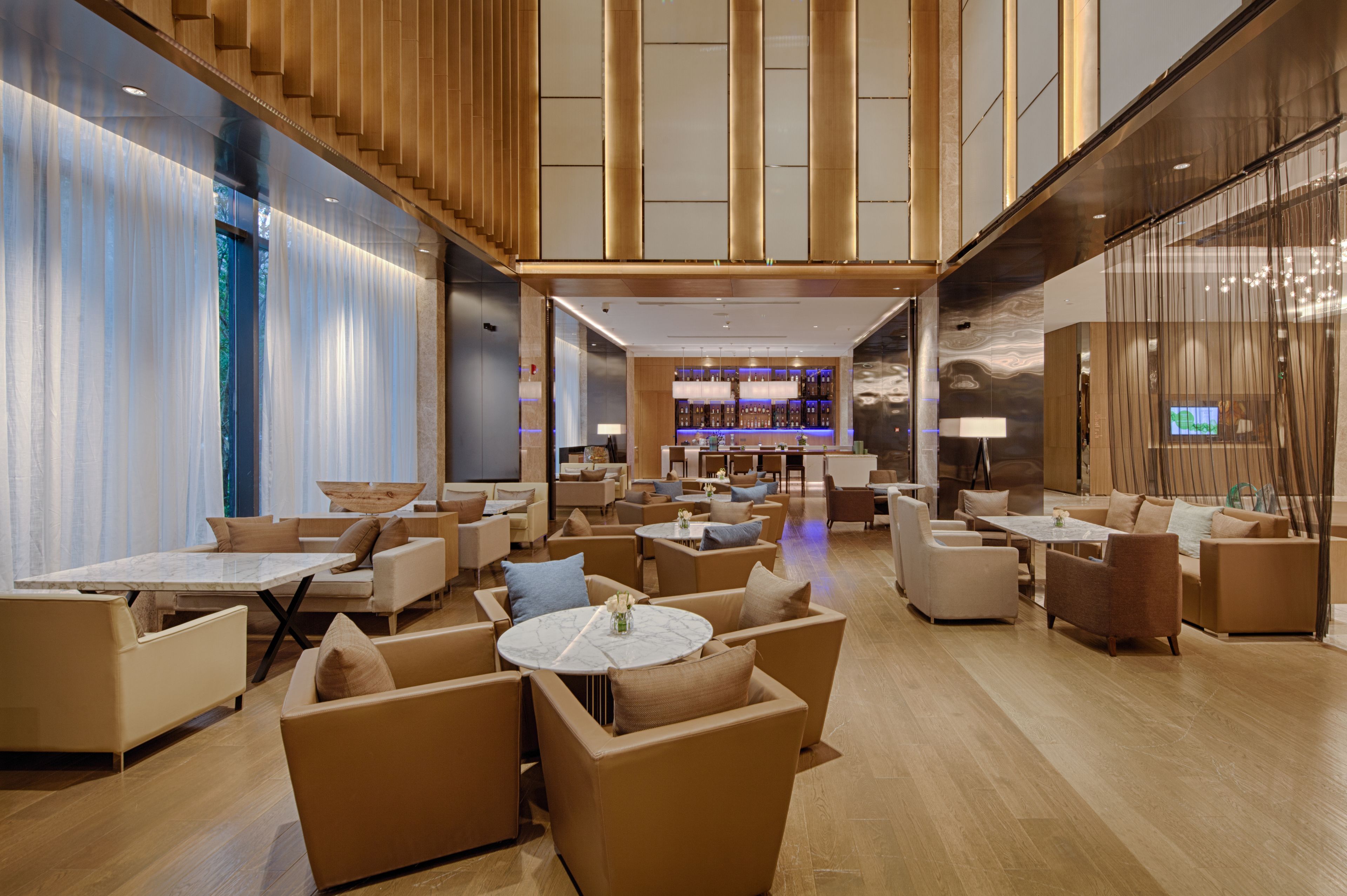 A spacious lobby with multiple seating areas, a bar, and a staircase.