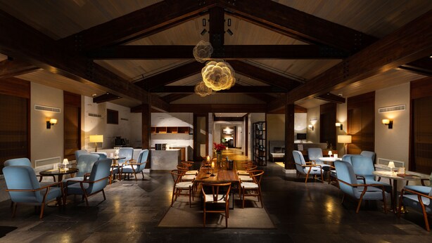 A spacious dining area with a high ceiling and exposed beams, featuring a central wooden table surrounded by blue upholstered chairs. - DoubleTree by Hilton Shanghai Hongqiao (Shanghai)