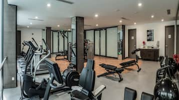 A modern gym with various exercise equipment, a wooden floor, and a reception area with a counter and decorative items.