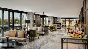 A modern hotel lobby with a marble floor, seating area with sofas and armchairs, a glass coffee table, and a fruit display. - DoubleTree by Hilton Shanghai Hongqiao (Shanghai)