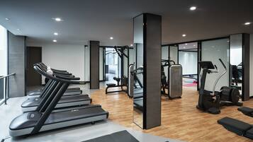 A gym with treadmills, weight machines, and a mirrored wall.