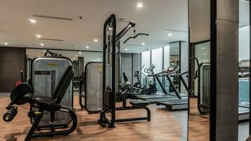 Une salle de sport moderne équipée de divers appareils d’entraînement, notamment un banc de développé couché, un support à squats et des tapis de course.