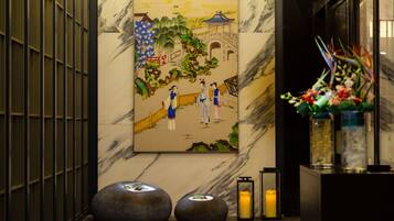 Ett traditionellt japanskt konstverk som föreställer ett landskap med figurer, placerat på en vägg av marmor.