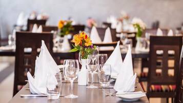 Un restaurante con mesas ordenadas, cada una con servilletas blancas, vasos transparentes y centros de mesa florales.