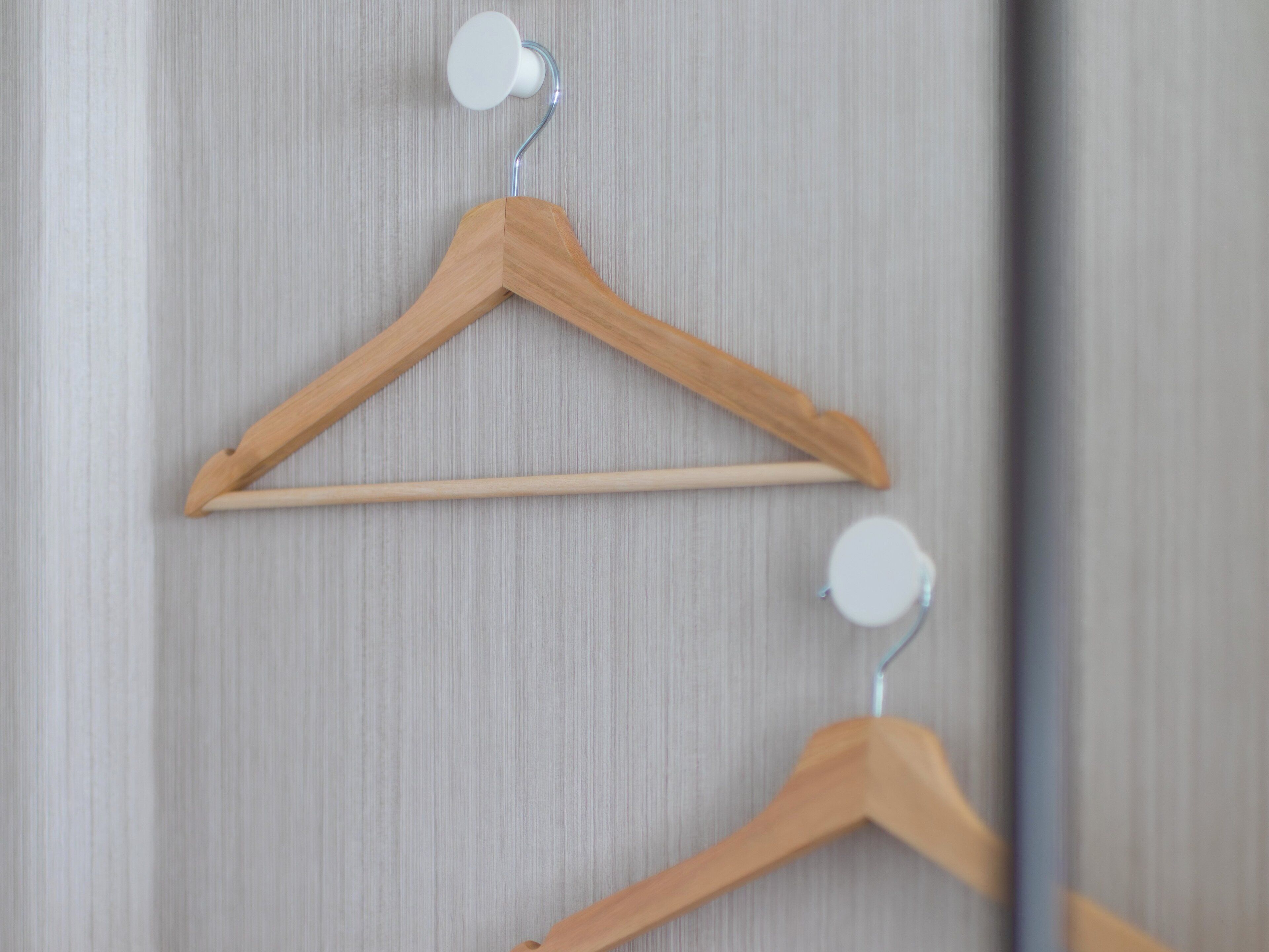 Wooden hangers on a wall with a vertical striped pattern.
