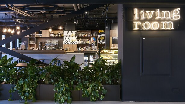 A modern bar area with a neon sign reading "living room" and a slogan "eat drink do good." - Good Hotel London (London)