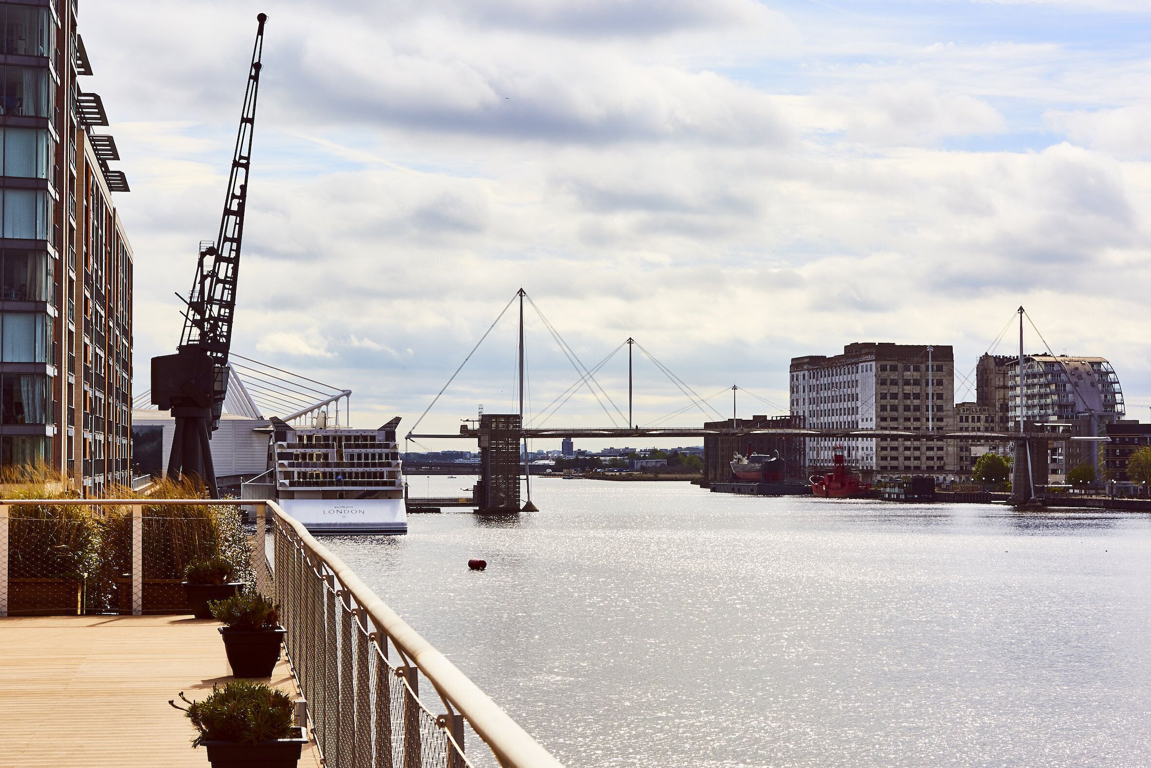 A riverside walkway with a view of a bridge and buildings.