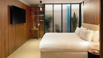 Una camera da letto moderna con un letto grande, una televisione a schermo piatto montata a parete e una porta vetrata scorrevole che dà su un balcone.