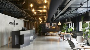 A modern hotel lobby with a reception desk, seating area, and large windows. - Good Hotel London (London)