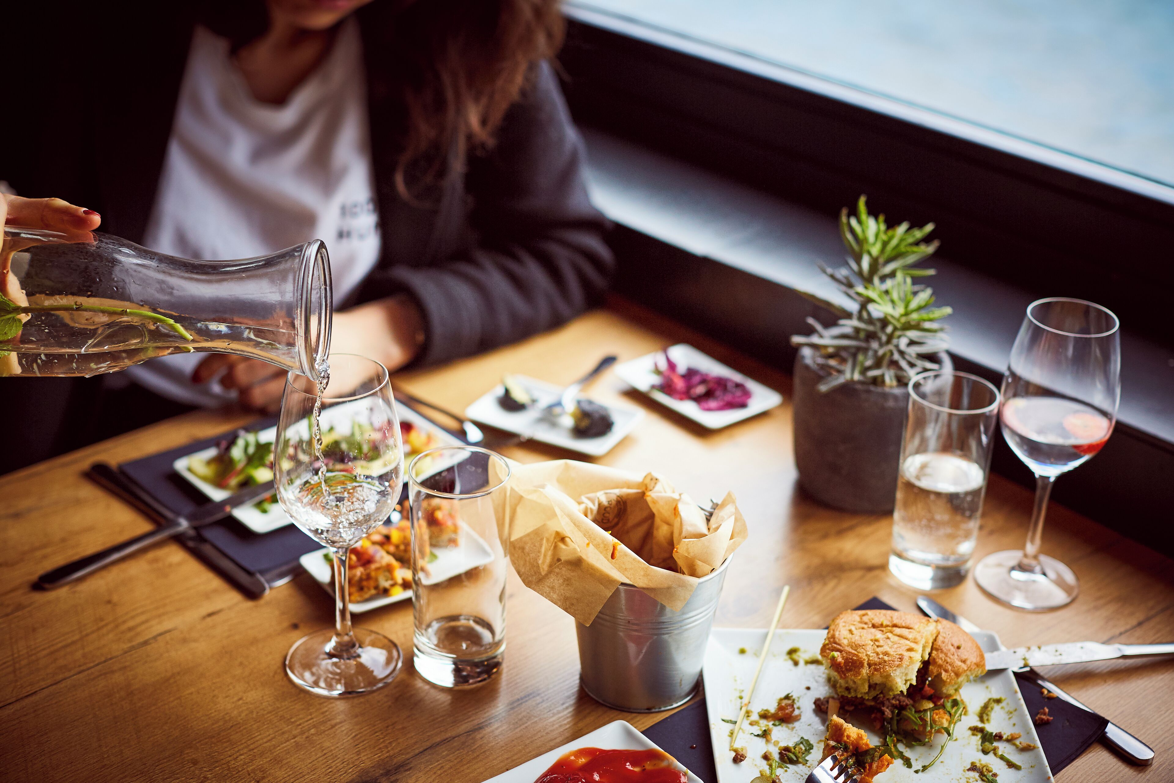 Een eettafel met verschillende gerechten, glazen en een fles wijn.