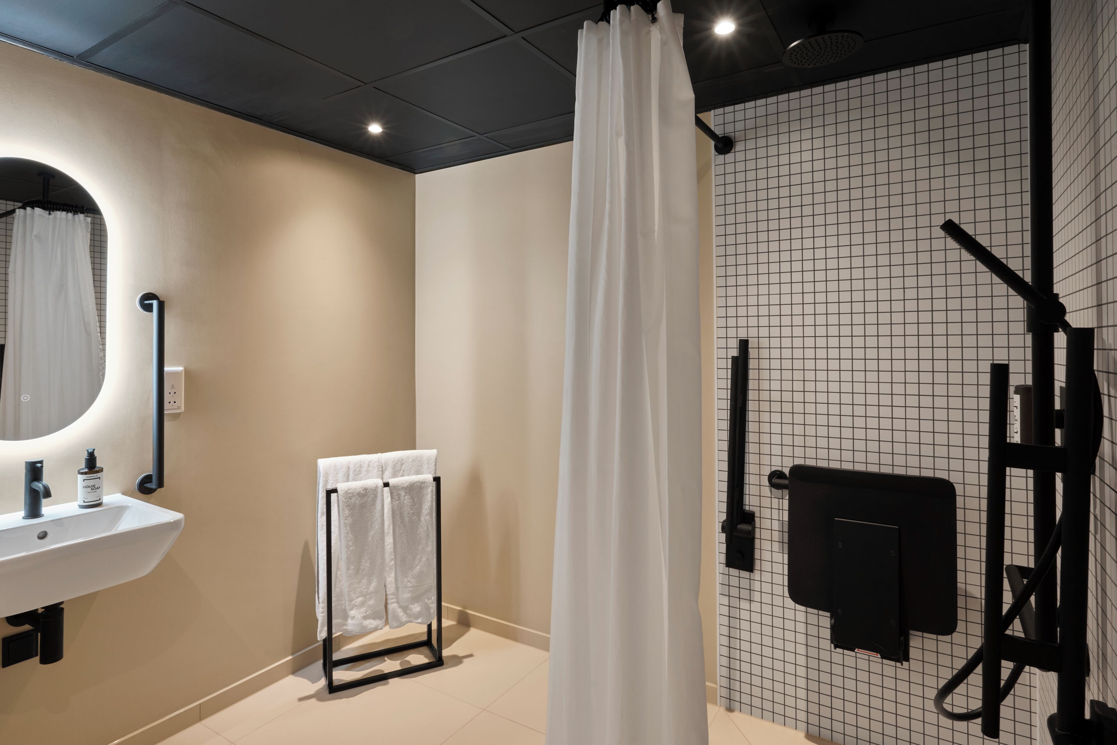 Un bagno moderno con lavandino, specchio, portasci, tenda da doccia e parete con motivo a griglia.