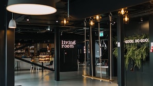 A modern interior with a bar area, seating, and a 'living room' sign. - Good Hotel London (London)