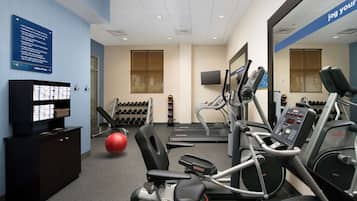 A gym with exercise equipment, a treadmill, and a red exercise ball.