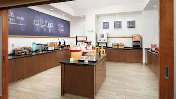 Una cocina moderna con armarios de madera, una isla central y una pared de pizarra con dibujos relacionados con la cocina.