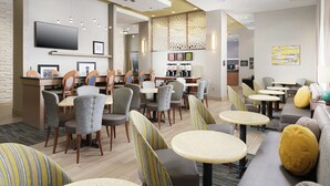 A modern hotel lobby with a bar area, seating arrangements, and a flat-screen TV mounted on the wall. - Hampton Inn by Hilton Wilmington Downtown (Wilmington)