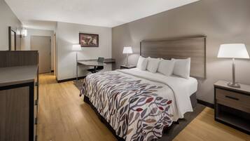 A hotel room with a bed, bedside tables, a desk, and a chair.