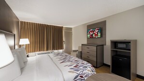 A hotel room with a large bed, a desk, a television, and a minibar. - Red Roof Inn Dumfries - Quantico (Dumfries)