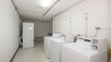 A laundry facility with multiple washing machines and dryers, a ventilation system, and a water heater.