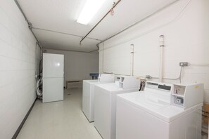 A laundry facility with multiple washing machines and dryers, a ventilation system, and a water heater. - Red Roof Inn Dumfries - Quantico (Dumfries)