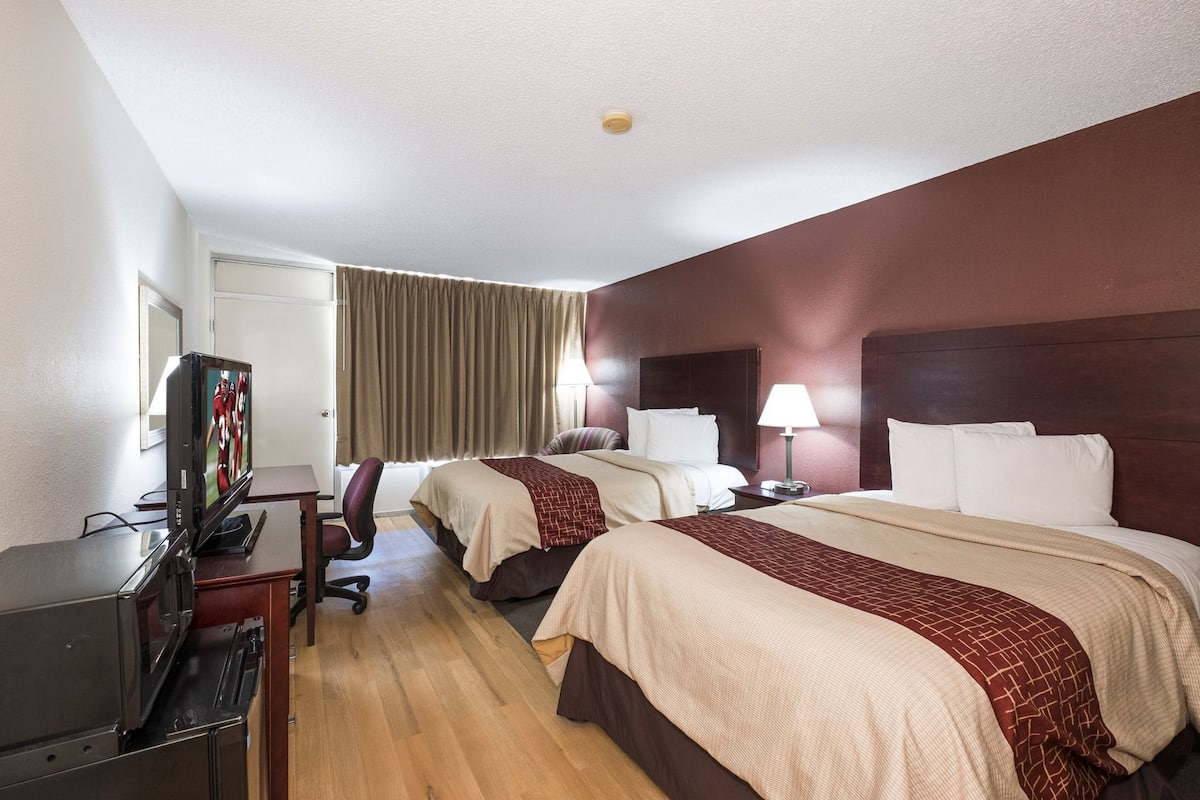 Une chambre d’hôtel avec deux lits, une télévision, un bureau et une chaise.